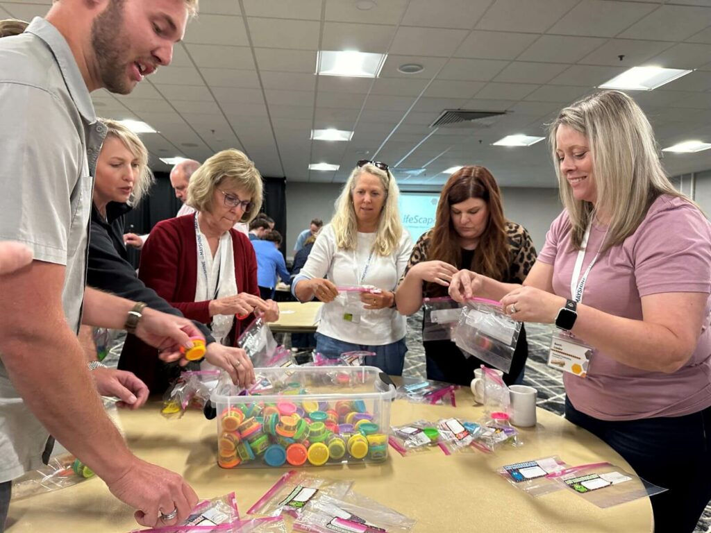 2024 Dealer Conference Humanitarian Event - group of fundraising dealership owners around a table putting together monster kits.